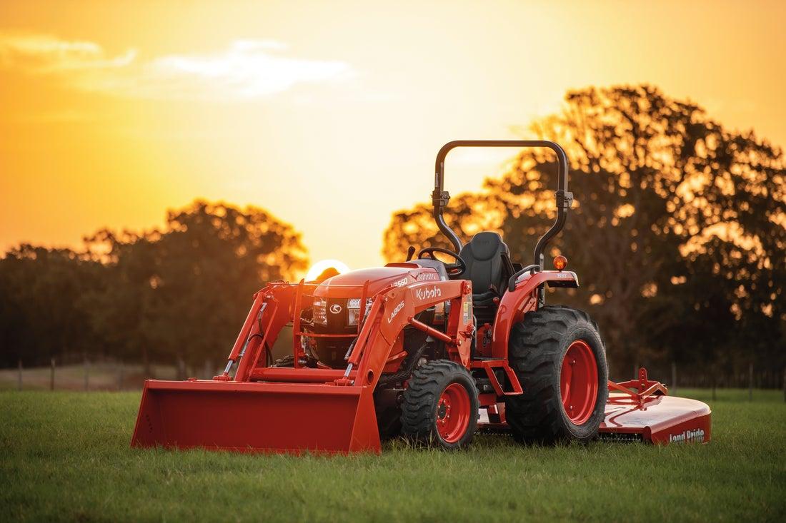 Compact tractor in a field with a beautiful sunset in the back