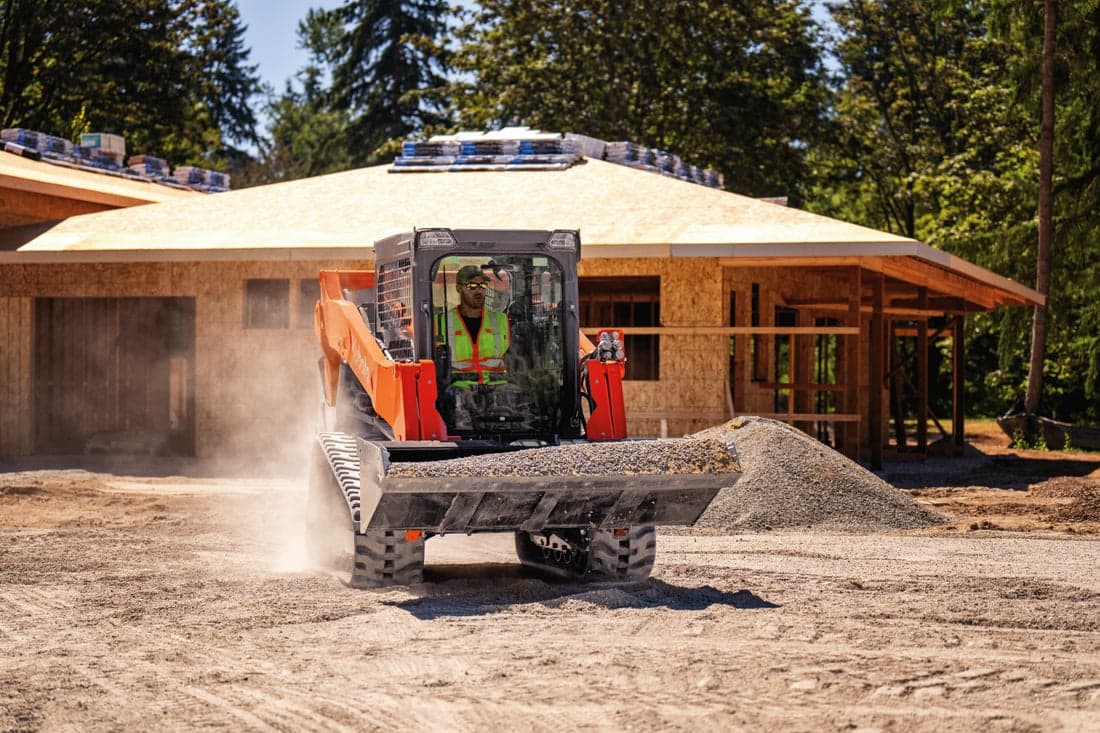 Man moving gravel with skid steer on a construction site
