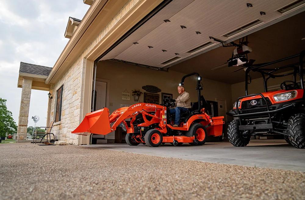 Man driving tractor of of a garage