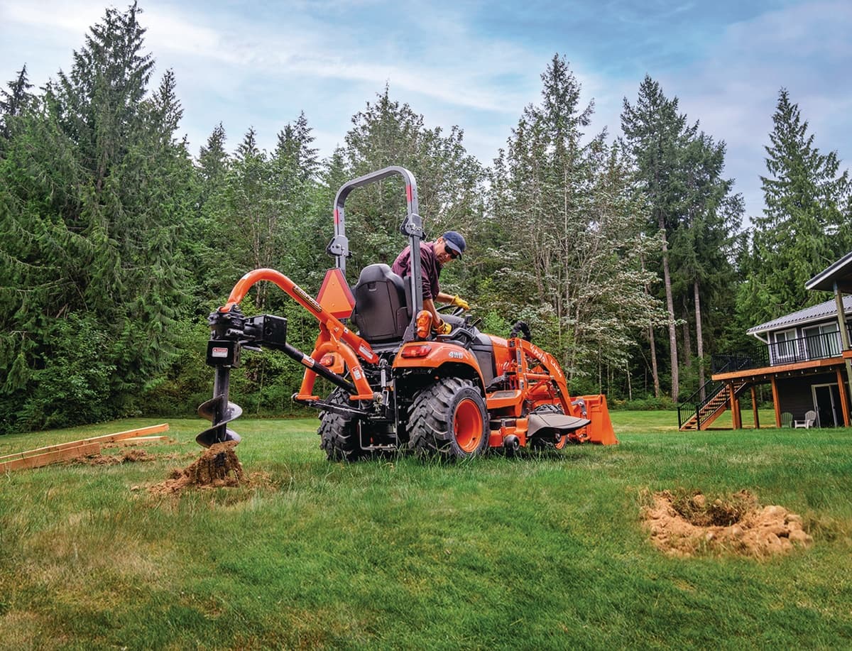 Person using rear auger implement on tractor