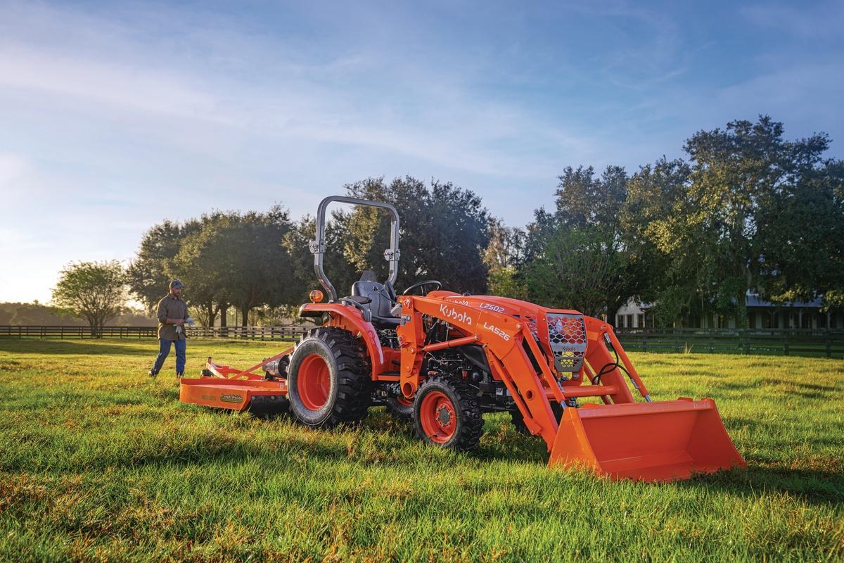 Man walking up behind tractor in a field