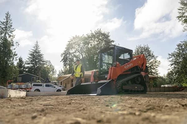 Man walking up towards skid steer on a construction site