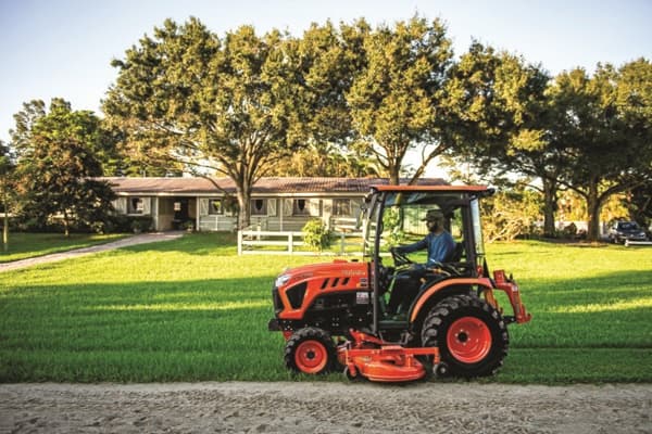 Man using tractor's mid-mount mower to mow grass