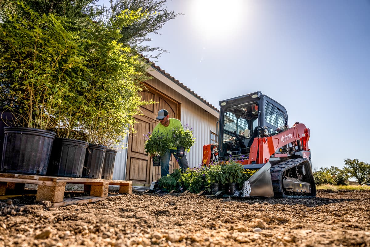 Man unloading potted plants from Kubota SVL65-2