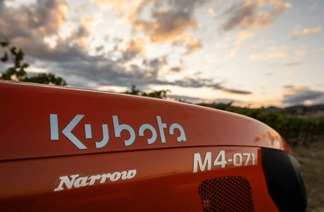 Kubota M4-071 Narrow badge on tractor hood at sunset in a vineyard