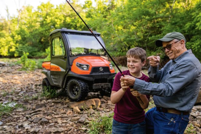 Kubota RTV520 utility vehicle parked streamside while a grandfather and grandson fish