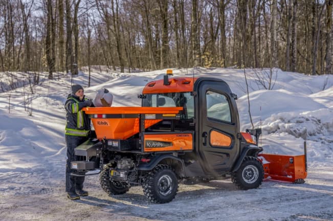 Kubota RTV-X CAB utility vehicle with enclosed cab, snow plow, and salt spreader attachment